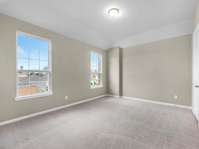 carpeted spare room with vaulted ceiling