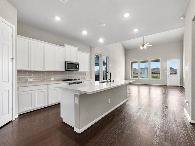 kitchen with white cabinetry, an island with sink, tasteful backsplash, and dark hardwood / wood-style flooring