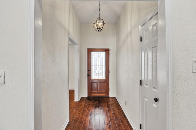 doorway to outside with dark wood-type flooring and a chandelier