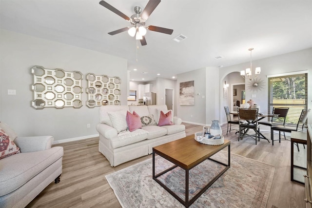 living room with ceiling fan with notable chandelier and light hardwood / wood-style floors