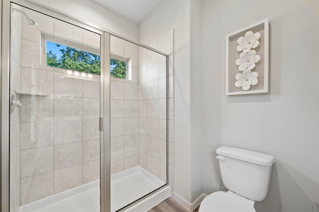 bathroom with hardwood / wood-style flooring, a shower with door, and toilet