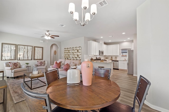 dining area featuring ceiling fan with notable chandelier and light hardwood / wood-style floors