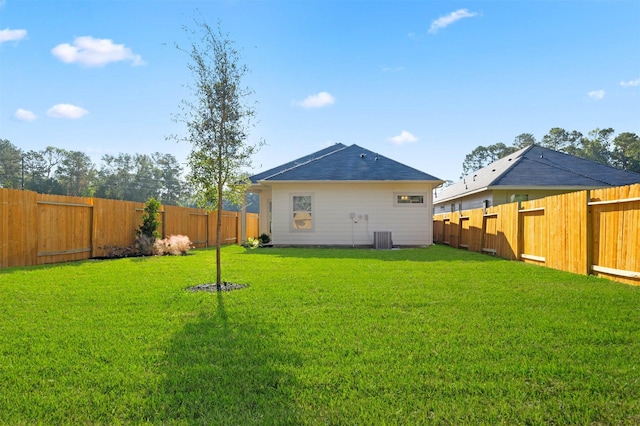 rear view of property featuring cooling unit and a lawn