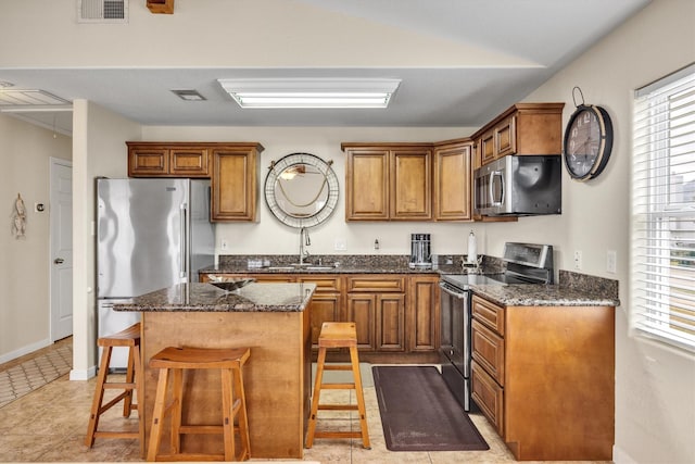 kitchen featuring appliances with stainless steel finishes, a center island, sink, and plenty of natural light