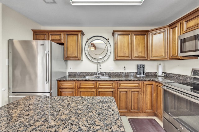 kitchen with sink, dark stone counters, and appliances with stainless steel finishes