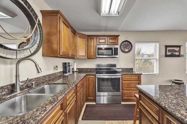 kitchen featuring appliances with stainless steel finishes, sink, and dark stone counters