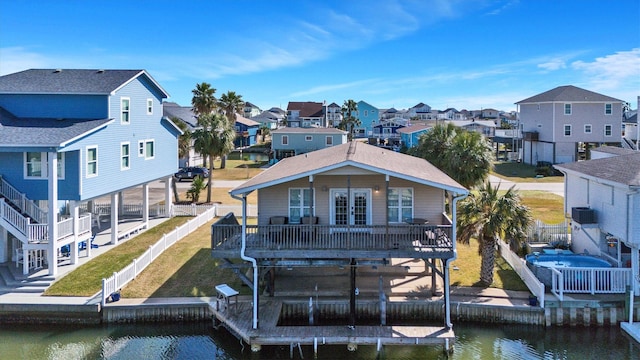 back of house with a lawn, a water view, central AC, and french doors