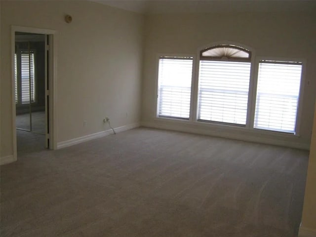 spare room with plenty of natural light and dark colored carpet