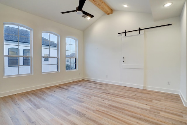 unfurnished room with light hardwood / wood-style flooring, lofted ceiling with beams, a barn door, and ceiling fan