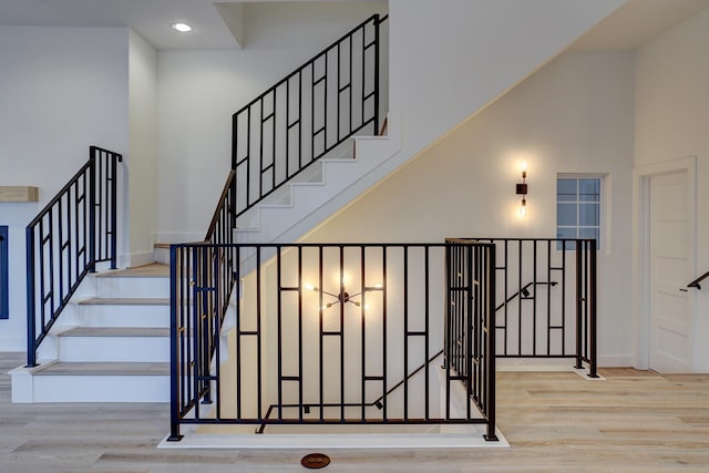 stairs with hardwood / wood-style flooring and a towering ceiling