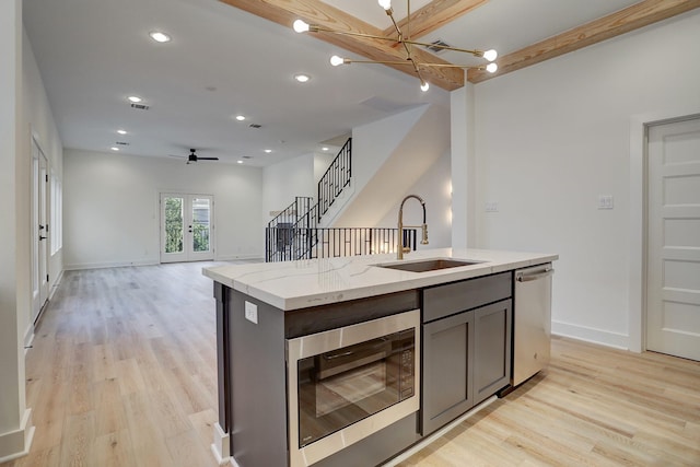 kitchen featuring sink, dishwasher, an island with sink, built in microwave, and french doors