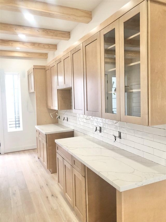 2221 Bevis St, Houston, TX 77008 - kitchen with light stone countertops, backsplash, light wood-style flooring, beamed ceiling, and glass insert cabinets