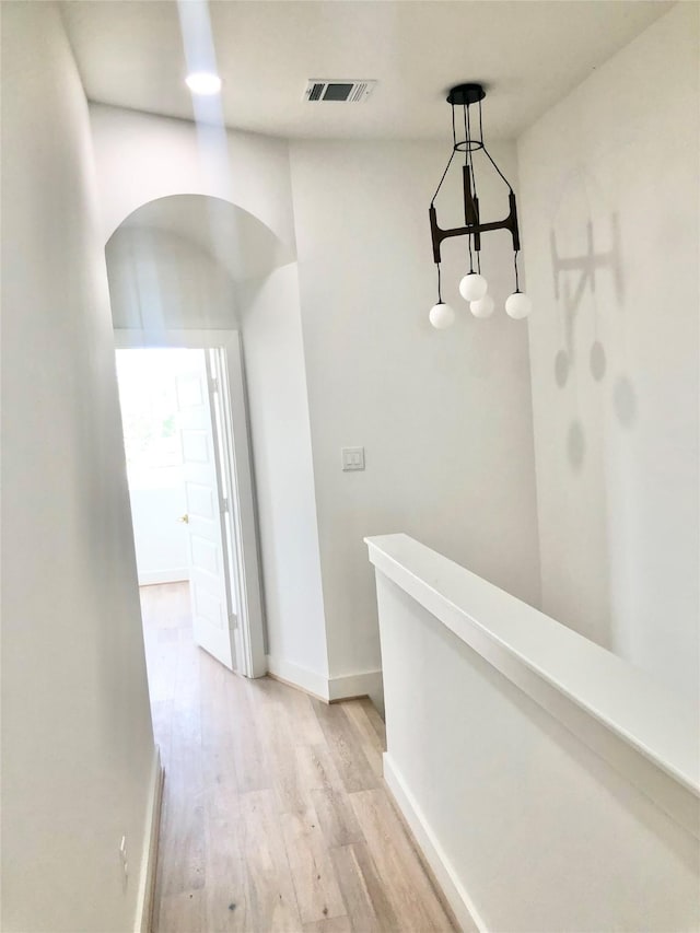 2221 Bevis St, Houston, TX 77008 - hall featuring light wood-style flooring, arched walkways, and an upstairs landing