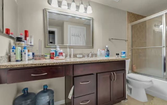 bathroom featuring vanity, toilet, and shower / bath combination with glass door