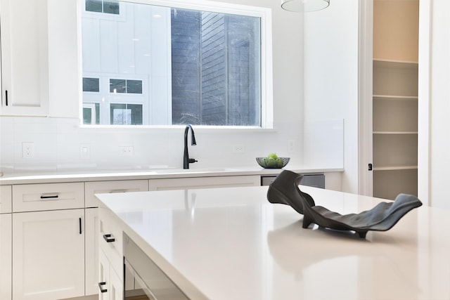 kitchen featuring a sink, visible vents, white cabinets, light countertops, and decorative backsplash