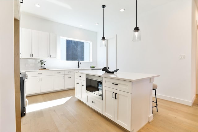 kitchen with light wood-style floors, a sink, white cabinets, and built in microwave