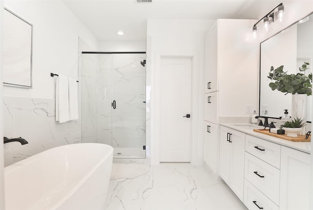 bathroom featuring marble finish floor, a marble finish shower, recessed lighting, a soaking tub, and vanity