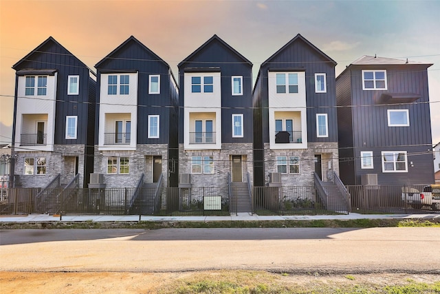 townhome / multi-family property with stone siding and a fenced front yard