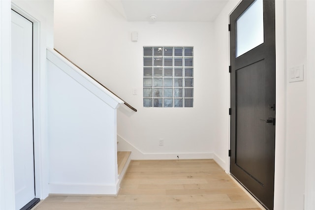 foyer featuring light wood-type flooring, stairway, and baseboards