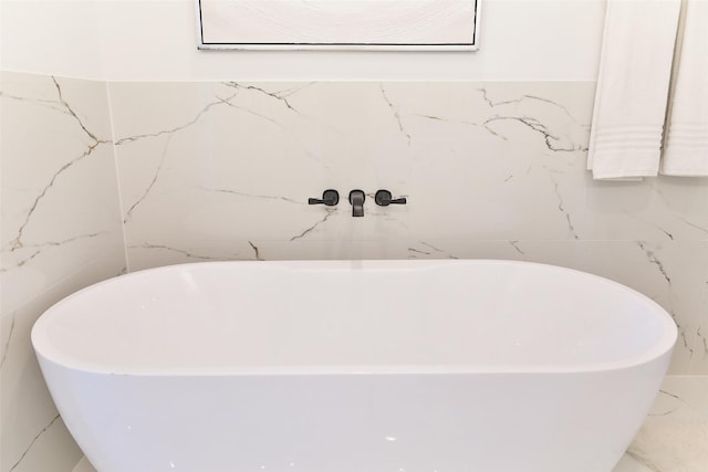 bathroom featuring marble finish floor and a freestanding bath