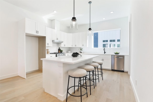 kitchen featuring white cabinetry, a kitchen breakfast bar, range, under cabinet range hood, and dishwasher