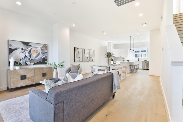 living room with light wood-style flooring, visible vents, and recessed lighting