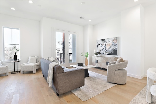 living room with light wood finished floors, recessed lighting, baseboards, and french doors