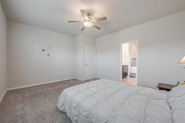 carpeted bedroom with ensuite bath and ceiling fan