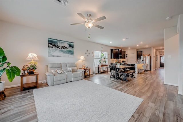 living room with light hardwood / wood-style floors and ceiling fan