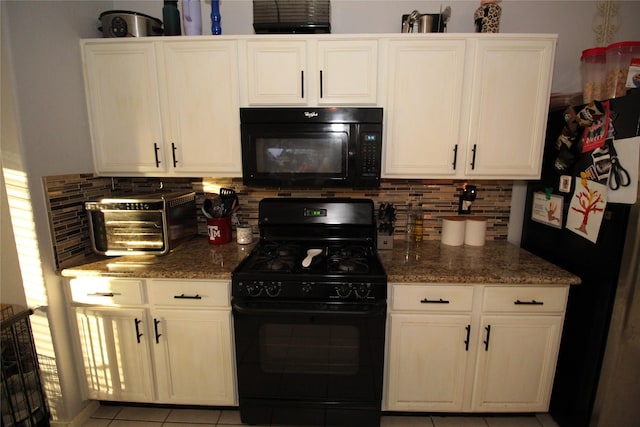 kitchen featuring dark stone countertops, light tile patterned floors, tasteful backsplash, and black appliances