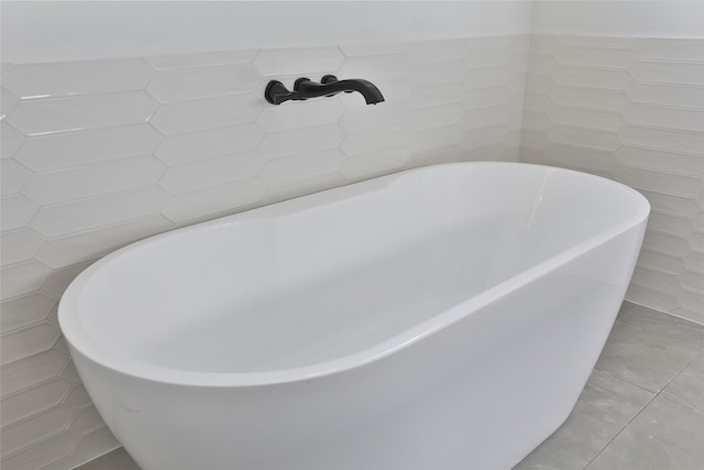 bathroom featuring a washtub, tile patterned floors, and tile walls