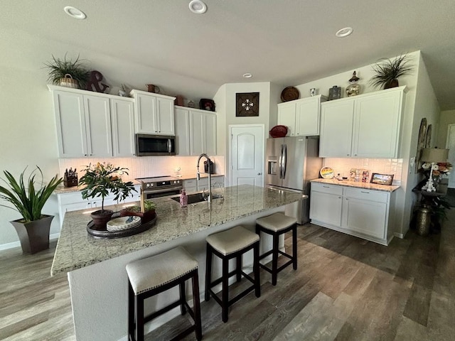 kitchen featuring stainless steel appliances, a kitchen island with sink, sink, and white cabinets