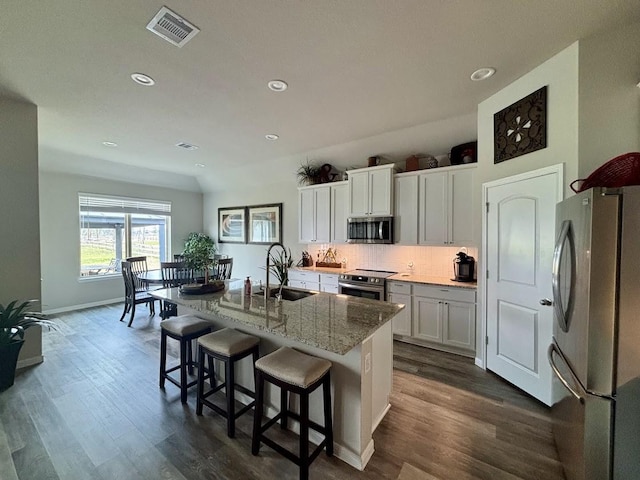 kitchen featuring sink, a breakfast bar area, stainless steel appliances, a kitchen island with sink, and white cabinets