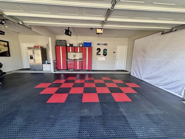 garage with a garage door opener and stainless steel fridge with ice dispenser