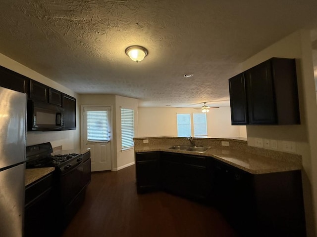 kitchen featuring sink, dark wood-type flooring, black appliances, a textured ceiling, and kitchen peninsula