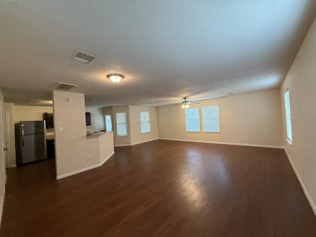 unfurnished living room with dark wood-type flooring, a healthy amount of sunlight, and a textured ceiling