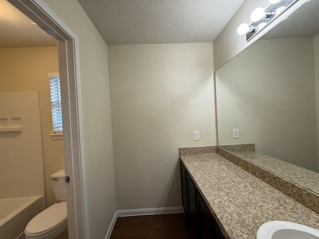 bathroom featuring wood-type flooring, vanity, toilet, a bath, and a textured ceiling