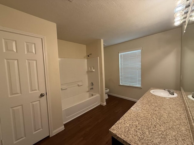 full bathroom with washtub / shower combination, toilet, a textured ceiling, vanity, and hardwood / wood-style flooring