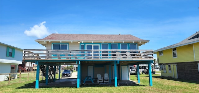 rear view of property with a carport, a yard, and a deck