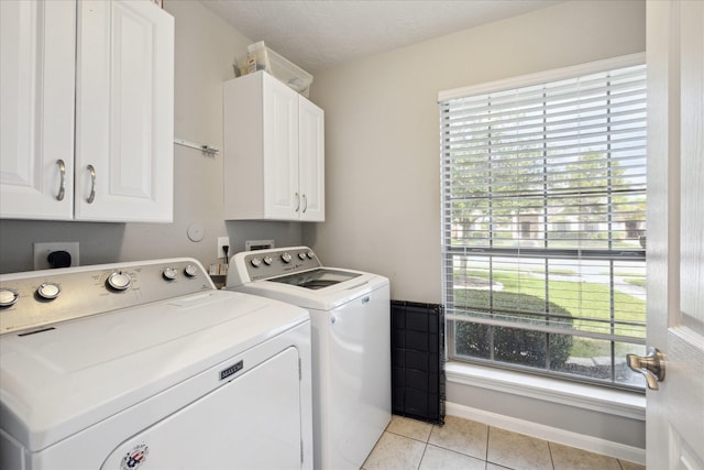 clothes washing area featuring plenty of natural light, cabinets, and washing machine and clothes dryer