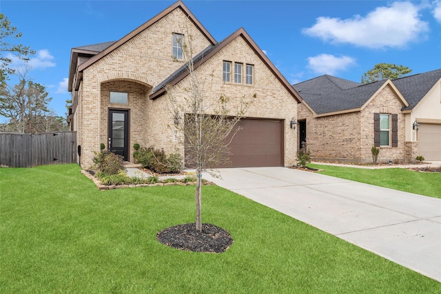 french country inspired facade featuring brick siding, a shingled roof, a front yard, fence, and driveway