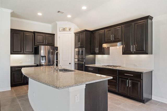 kitchen featuring light tile patterned flooring, sink, light stone counters, appliances with stainless steel finishes, and an island with sink