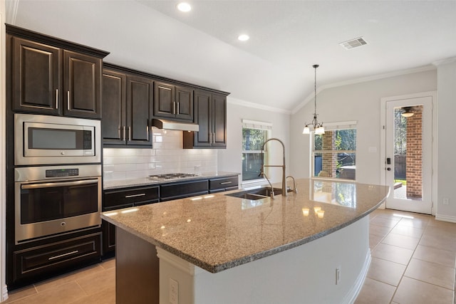 kitchen with lofted ceiling, sink, stainless steel appliances, light stone countertops, and a center island with sink