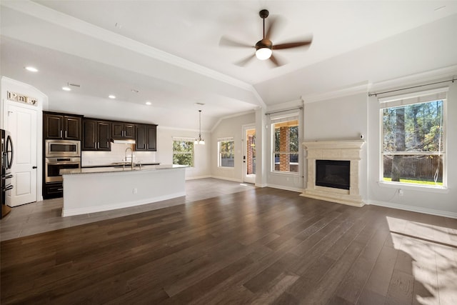 unfurnished living room with vaulted ceiling, dark hardwood / wood-style floors, sink, ceiling fan, and crown molding