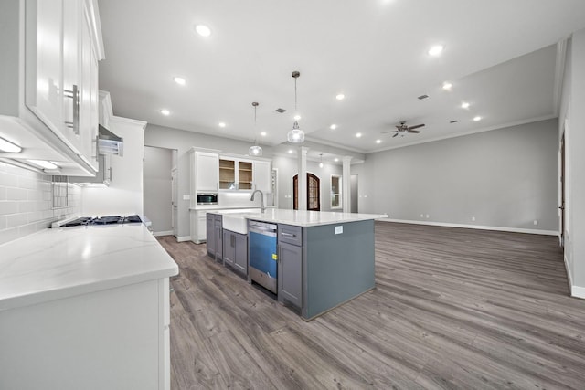 kitchen with stainless steel appliances, white cabinetry, a center island with sink, and hanging light fixtures