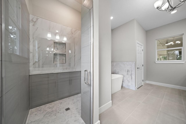 bathroom featuring tile walls, a stall shower, tile patterned flooring, a freestanding tub, and baseboards