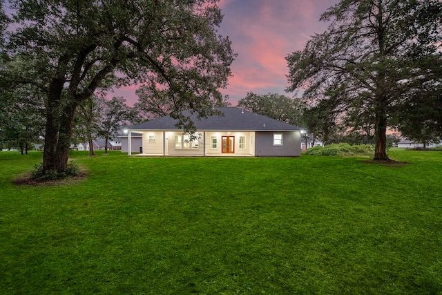 back of property at dusk featuring a yard