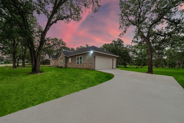 single story home with an attached garage, stone siding, driveway, a lawn, and stucco siding