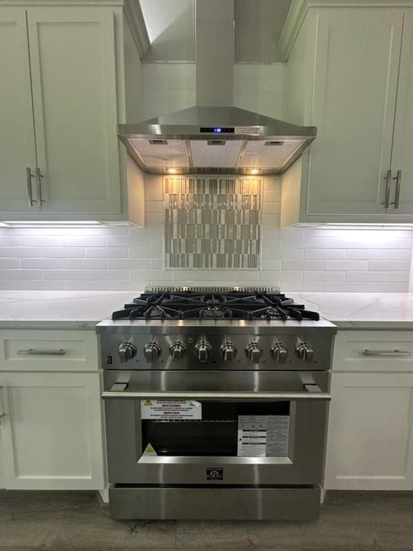 kitchen featuring dark wood-style flooring, exhaust hood, stainless steel stove, and decorative backsplash