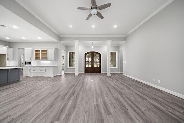 unfurnished living room with light wood-style flooring, visible vents, baseboards, french doors, and decorative columns